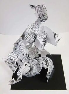 an abstract sculpture made out of paper on top of a black base and white background