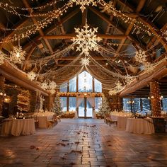 the inside of a barn decorated with lights and snowflakes on the ceiling, along with tables covered in white tablecloths