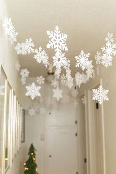 snowflakes are hanging from the ceiling in front of a christmas tree and hallway