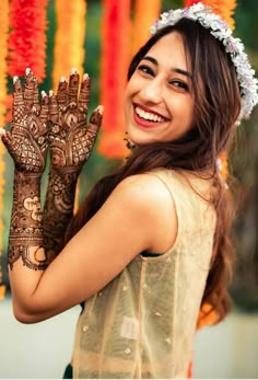 a woman is smiling and holding her hands up to show the henna on her hand