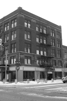 a black and white photo of an old building on the corner of a city street