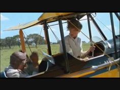 two boys are sitting in an airplane and one boy is looking out the window while another boy looks on