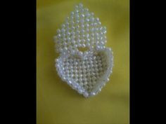 a white beaded heart shaped brooch on a yellow background