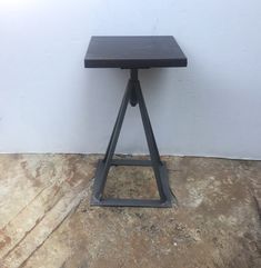 a small black table sitting on top of a floor next to a white walled wall