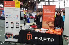 two people standing next to a table with orange items on it at an indoor event