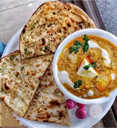 a bowl of soup with pita bread on the side