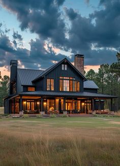 a large black house sitting on top of a lush green field under a cloudy sky