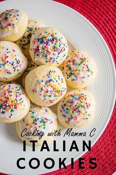 some cookies with sprinkles are on a white plate next to a red table cloth