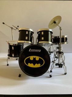 a batman drum set on a white surface with drums and cymbals in the background