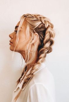 a woman with long blonde hair in a fishtail braid, wearing a white shirt