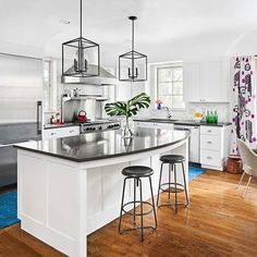 a kitchen with white cabinets and stainless steel appliances, including an island in the center