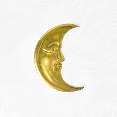 a golden crescent moon with a face on it's side against a white background