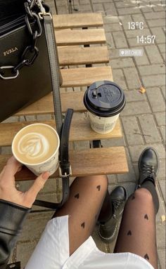 a person sitting at a table with a cup of coffee and a handbag on it