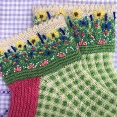 three knitted socks with flowers on them sitting on a checkered tablecloths