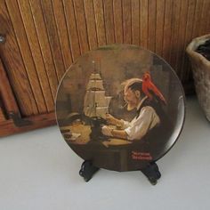 a plate with a painting of a man at a table next to a potted plant