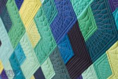 a close up of a quilt on a bed with many different colored blocks in it