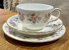 a tea cup and saucer sitting on top of a wooden table next to a plate