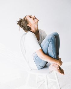 a woman sitting on top of a white chair with her mouth open and eyes closed