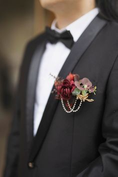 a man in a tuxedo is wearing a boutonniere with flowers on it