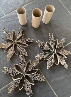 three silver snowflakes sitting on top of a tile floor next to two cups