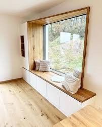 an empty room with a large window and wooden bench in front of the windowsill