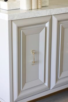 a white cabinet with a gold handle on it's door and some books in the background