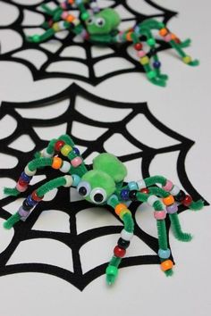 two green toy crabs sitting on top of a spider web net with eyes and legs