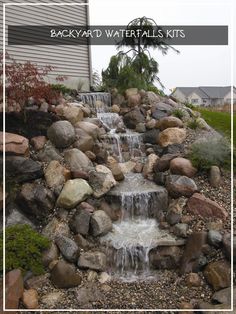 a small waterfall in the middle of a rock and gravel garden area with rocks surrounding it