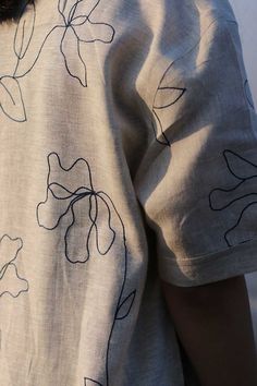 the back of a woman's shirt that has flowers on it and black outline