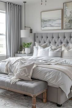 a large bed sitting in a bedroom next to a window with gray curtains and pillows