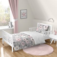 a child's bed with pink and white decor in a room that has hardwood floors