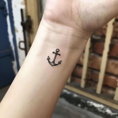 an anchor tattoo on the wrist is shown in black ink, and has a small white dot