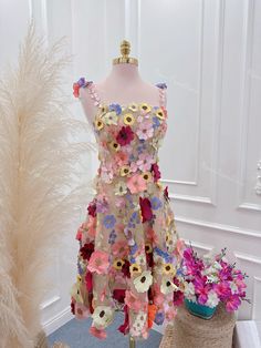 a dress made out of paper flowers on a mannequin next to a plant