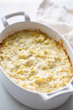 a white casserole dish filled with cheese and sauce on top of a table