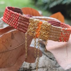 two bracelets with chains hanging from them sitting on top of some leafy leaves