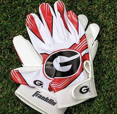 a pair of white and red gloves laying on top of green grass