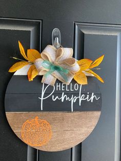 a wooden sign that says hello pumpkin hanging on a door with an orange and green bow