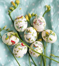 six painted eggs sitting on top of green stems