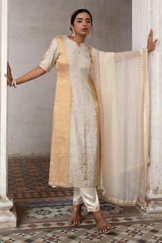 Silver, gold kurta with stripe pattern and zardozi embroidered neckline and hem. Paired with ivory pant and dupatta.
Components: 3
Pattern: Embroidery
Type Of Work: Stripe, zardozi
Neckline: Notched
Sleeve Type: Half
Fabric: Tissue, Gajji Silk, Organza, Lining: Shantoon
Color: Silver,Gold
Other Details: 
Tassel bordered sheer dupatta
Back keyhole
Embroidery on pant hem
Occasion: Sangeet - Aza Fashions Organza Kurta, Sheer Dupatta, A Line Kurti, Kurta Pant Set, Salwar Kamiz, A Line Kurta, Embroidery Suits Design, Elegant Saree, Embroidery Designs Fashion