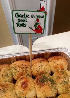 a tin pan filled with baked goods on top of a table next to a sign that says garlic in your rolls