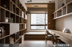 a room with wooden shelves and bookshelves filled with books next to a window