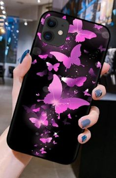 a woman holding up her phone case with pink butterflies on it