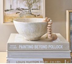 two books stacked on top of each other next to a bowl with rocks in it