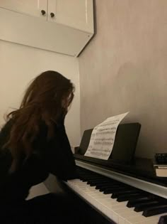 a woman sitting at a piano playing music