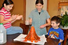 two children and an adult standing around a table with orange cones on top of it