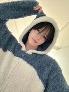 a young woman wearing a blue and white animal onesize hoodie is posing for the camera