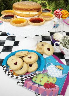 a table topped with lots of cookies and pastries on top of a checkered table cloth