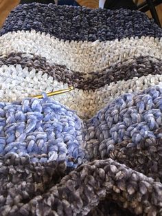 a crocheted blanket is laying on the floor next to a pair of scissors