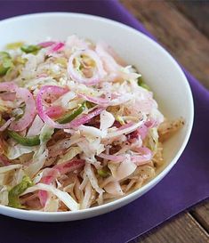 a white bowl filled with coleslaw on top of a purple napkin