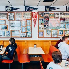 people sitting at tables in a restaurant with posters on the wall